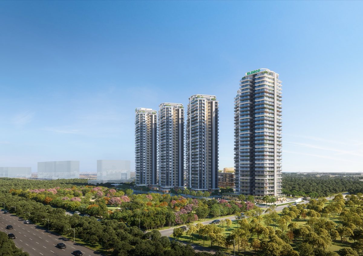 Towers rising above the green belt and the road in front
